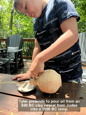 Tyler pretends to pour oil from an 800 BC clay vessel from Judea into a 1500 BC lamp